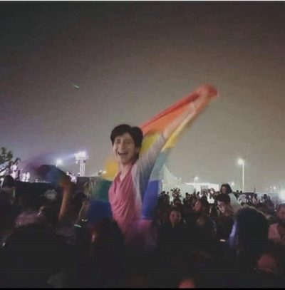 Hegazy raising the pride flag at a rock concert in Cairo, 2017. She was arrested for this action a week after the concert. Photo courtesy of Twitter)